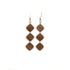 A pair of smoothed wooden drop earrings features three diamond pieces inlaid with bronze.  Each piece is handmade and unique. Placement and colors may vary and are not guaranteed but will resemble the piece shown.      2" long x 0.5" wide     Ear hook is bronze and nickle free.
